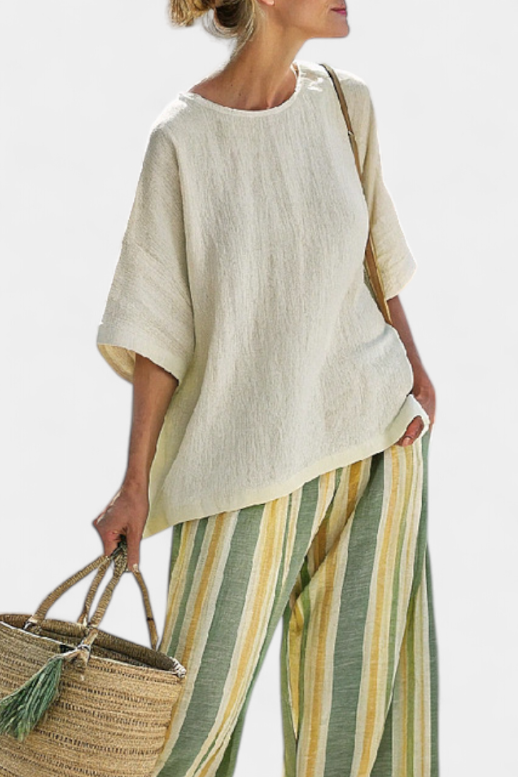 Beige linen tunic-style top with wide sleeves, worn with striped wide-leg trousers