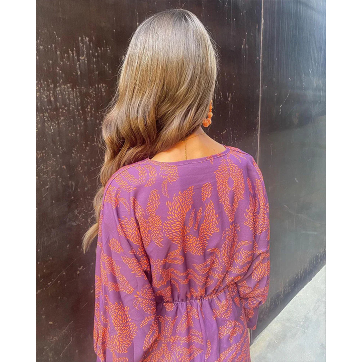 Back of boho elegance dress in purple with orange leaf print, long sleeves, tied waist