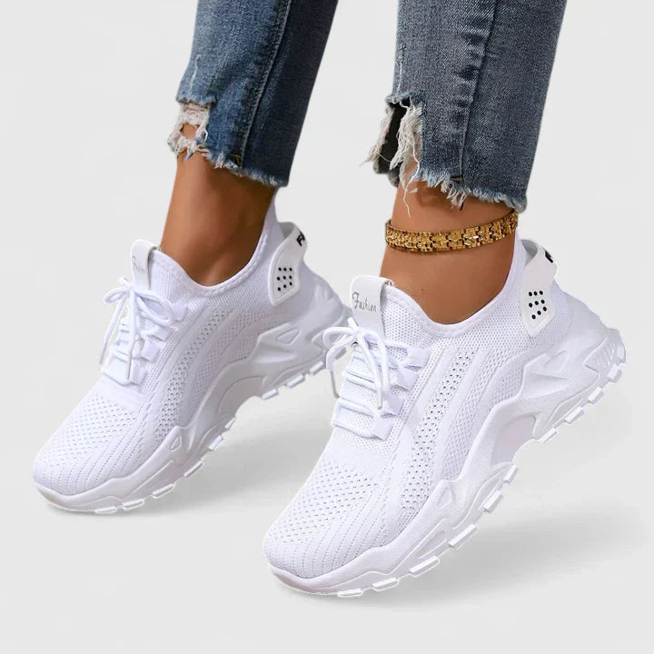 White orthopedic sneakers with breathable knit upper, lace-up front, and cushioned soles.