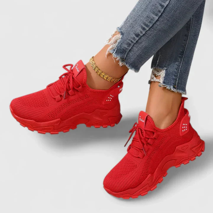 Red orthopedic sneakers with knit upper, lace-up front, and cushioned soles with tread.