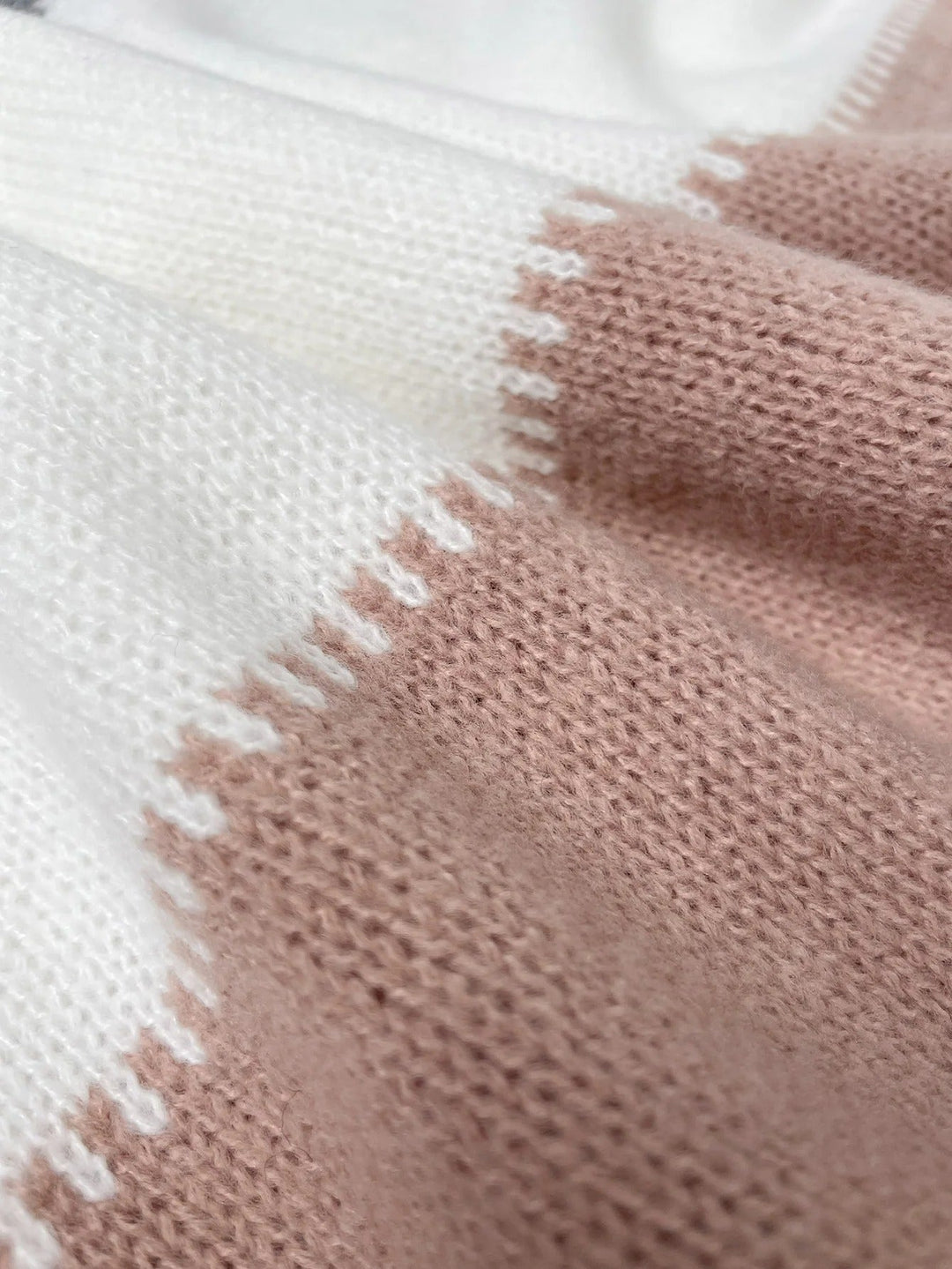 PANTHERA™ knit sweater close-up with blush-pink panel and white stitched edge detail
