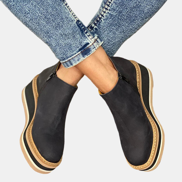 Black ankle boots with side elastic panels and platform sole with tan and white stripes.