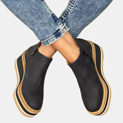 Black ankle boots with side elastic panels and platform sole with tan and white stripes.