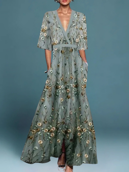 Floral maxi dress in sage teal with scattered cream-gold blossoms, deep V-neck, waist sash