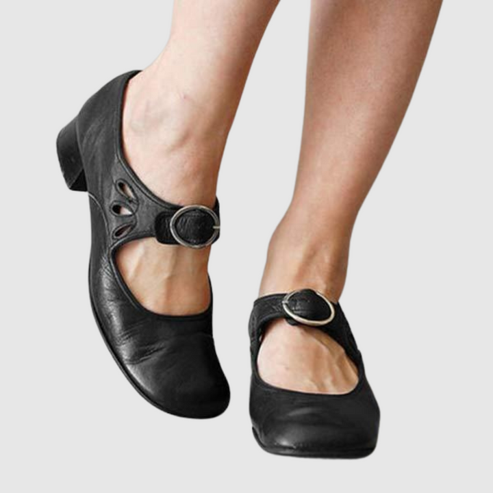 Black leather Mary Jane flats with oval cutout strap and round metal buckle