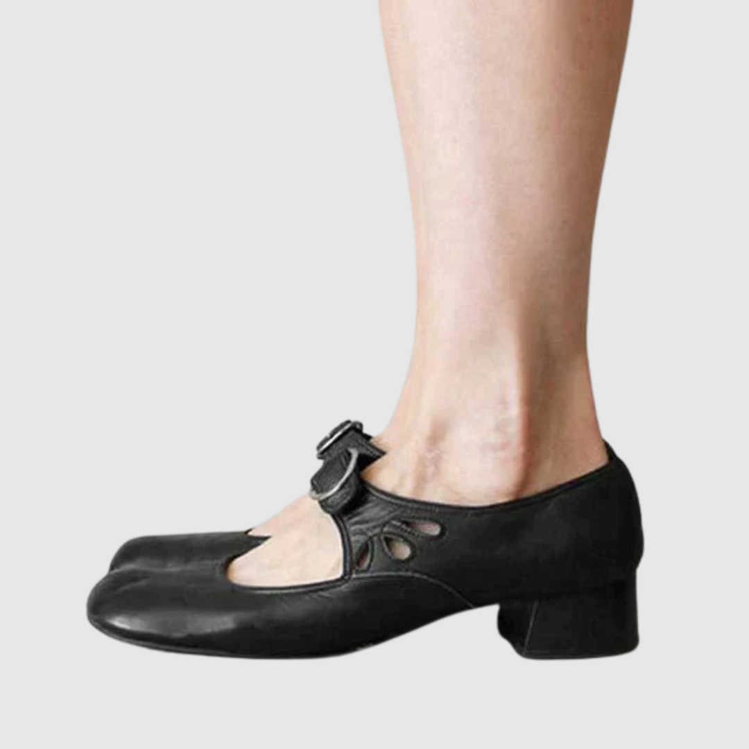 Black leather Mary Jane flats side view with oval cutout strap and metal buckle