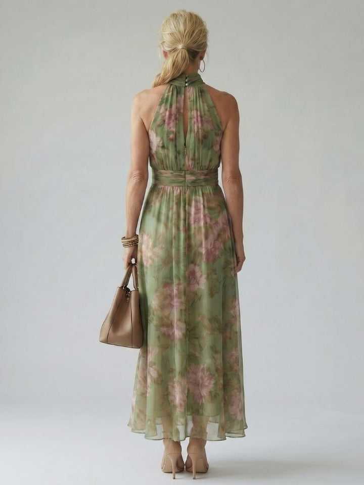 Back view of sage green gathered halter midi dress with pink floral print and tied waist