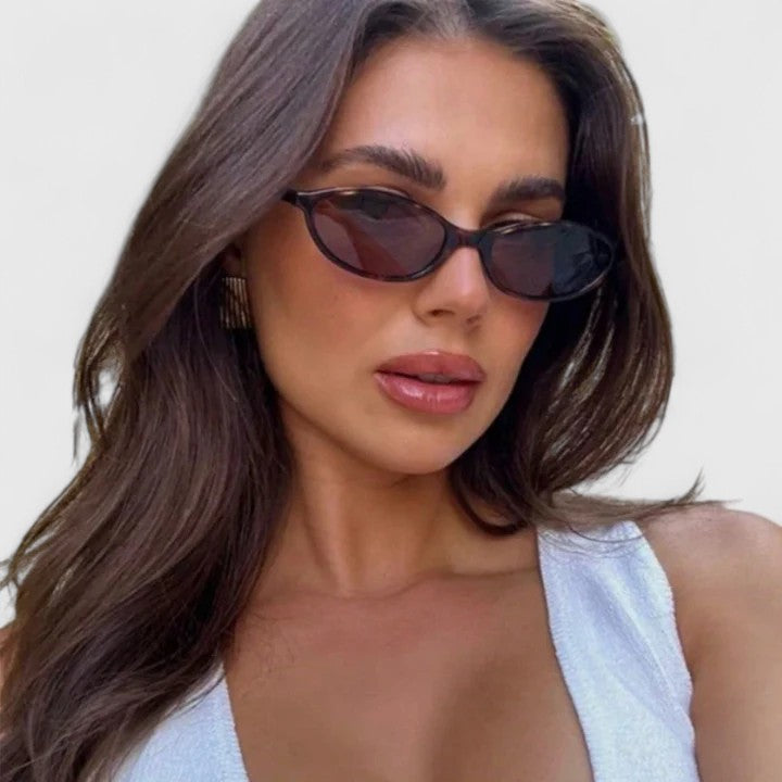 Sunglasses on model with black frames and dark lenses, rounded cat-eye silhouette