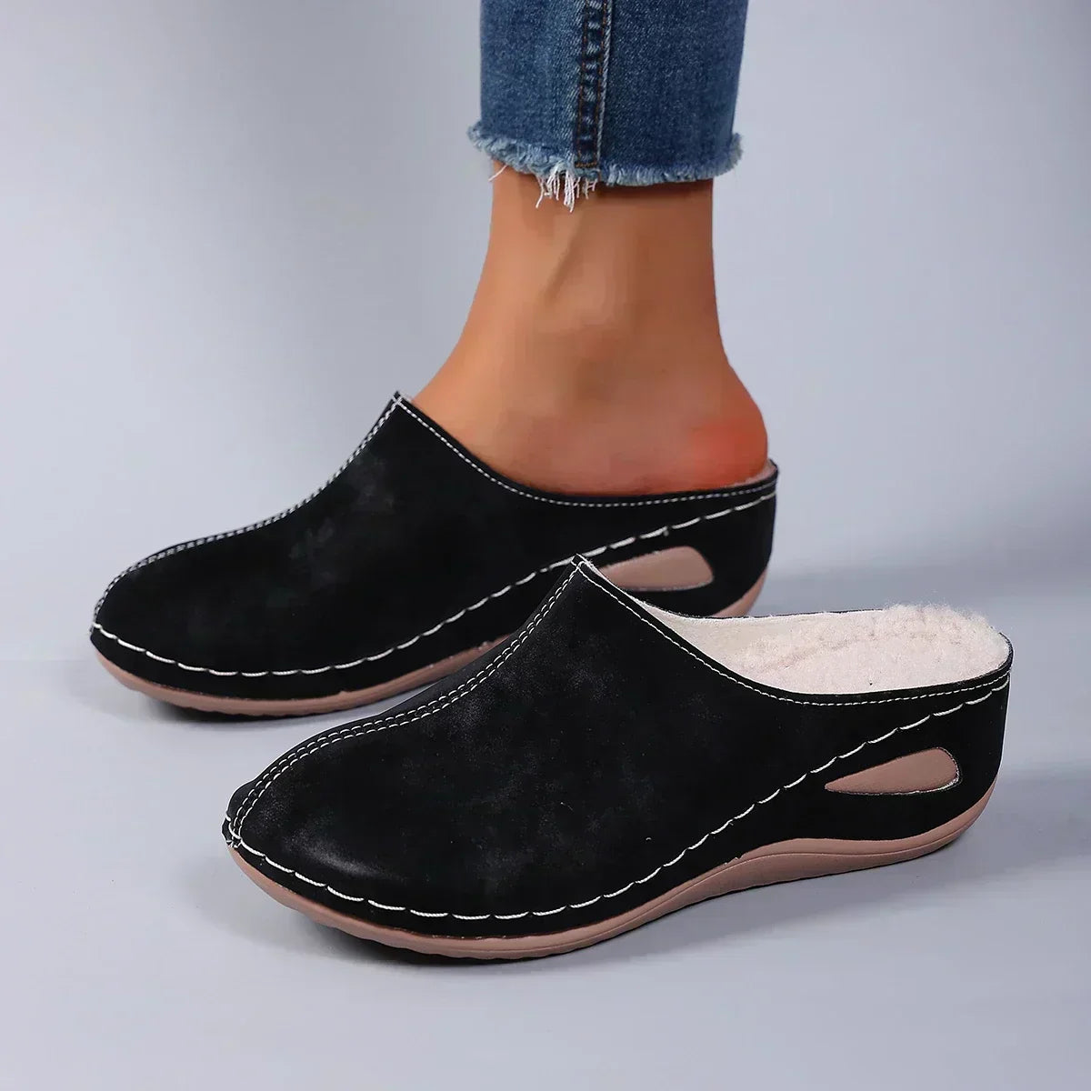 Black orthopedic mules on feet, suede-like upper with cutout instep and padded insole