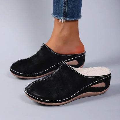 Black orthopedic mules on feet, suede-like upper with cutout instep and padded insole