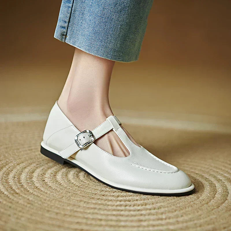 Light beige low-heeled Mary Jane pumps with T-strap and silver buckle, rounded toe.