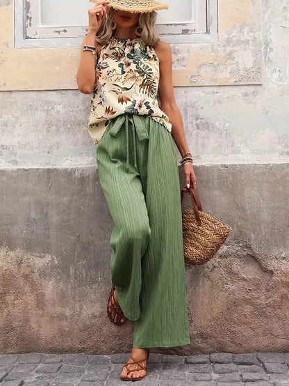Two-piece set with sleeveless floral blouse and emerald green wide-leg pants, tied waist