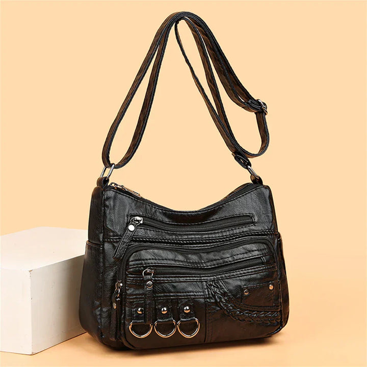 Black multi-layer crossbody bag with stacked zip compartments and front braid detail