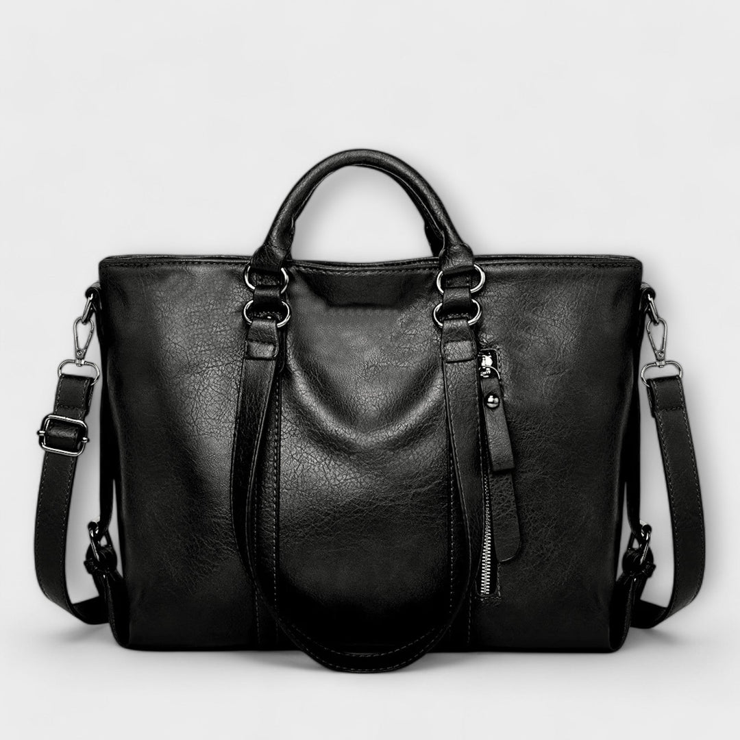 Large leather bag with top handles, side zippers, and crossbody straps in black.