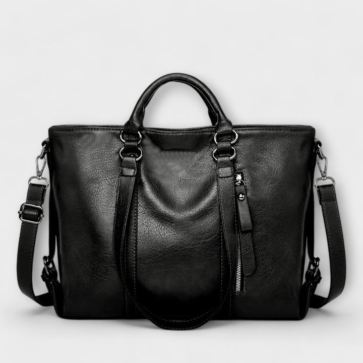 Large leather bag with top handles, side zippers, and crossbody straps in black.
