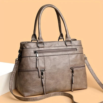Light grey leather women’s tote bag with double handles, front zip pocket and side straps