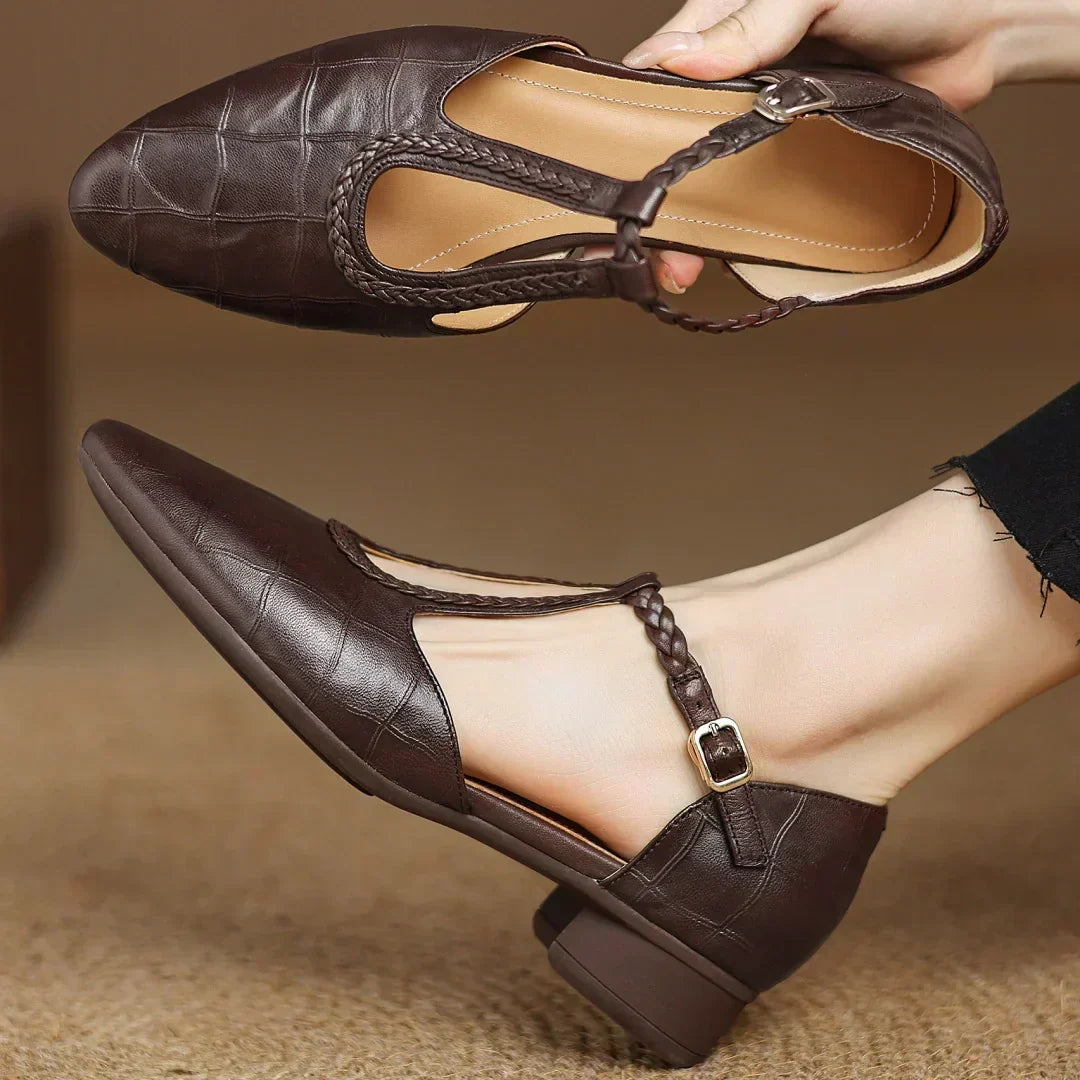Brown leather Mary Jane flat with ankle strap, buckle closure, and braided edge trim