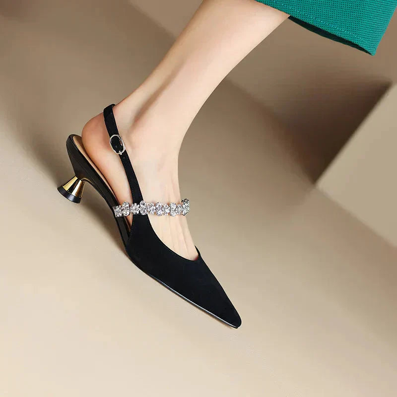 Black pointed-toe pumps with rhinestone strap and gold block heel