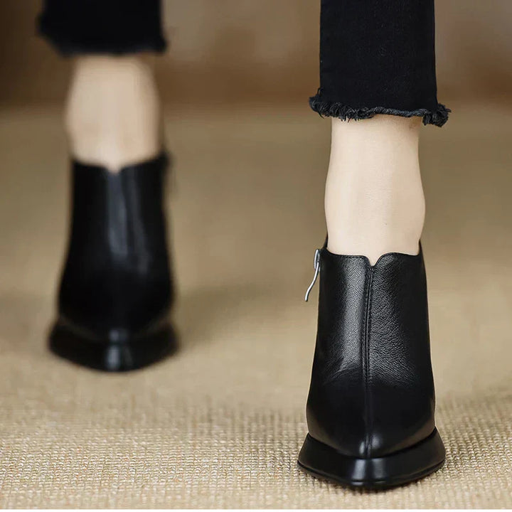 Black leather-look heeled pumps with back heel view and side zipper pull