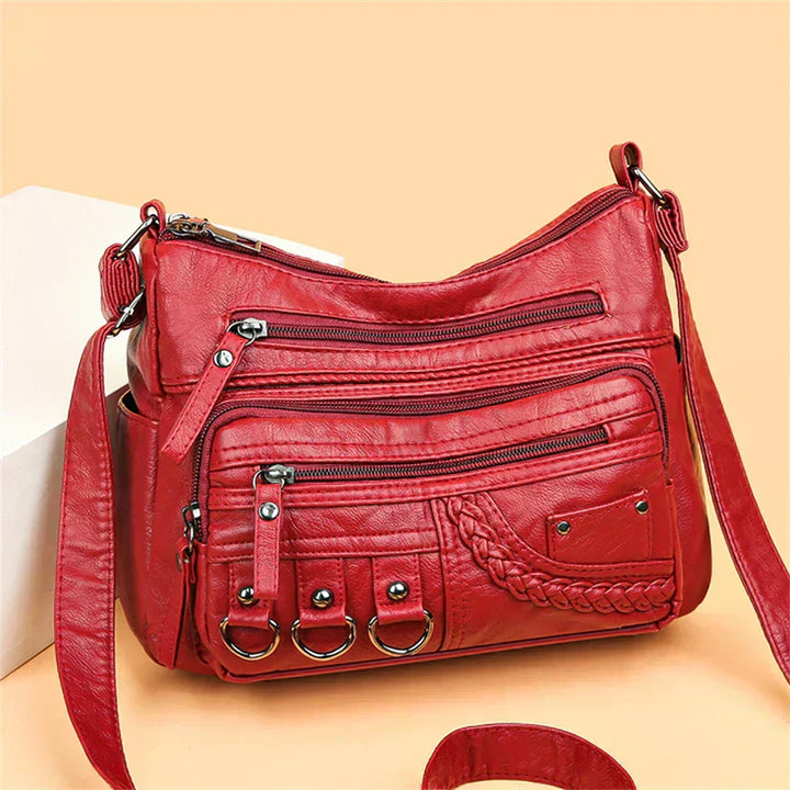 Red crossbody bag with woven panel, front zipper pockets, and hanging ring hardware