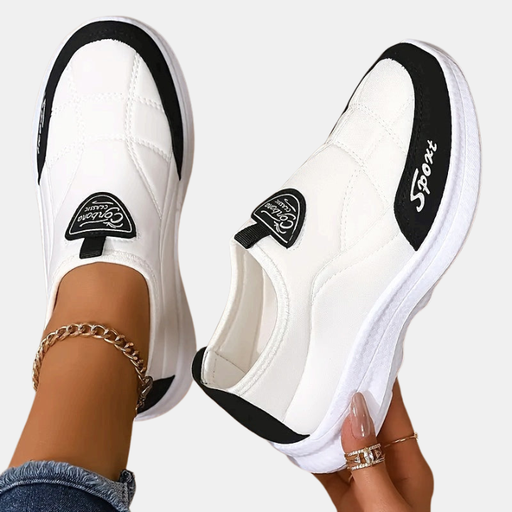 White slip-on sneakers with black accents, round toe, and heel tab patch