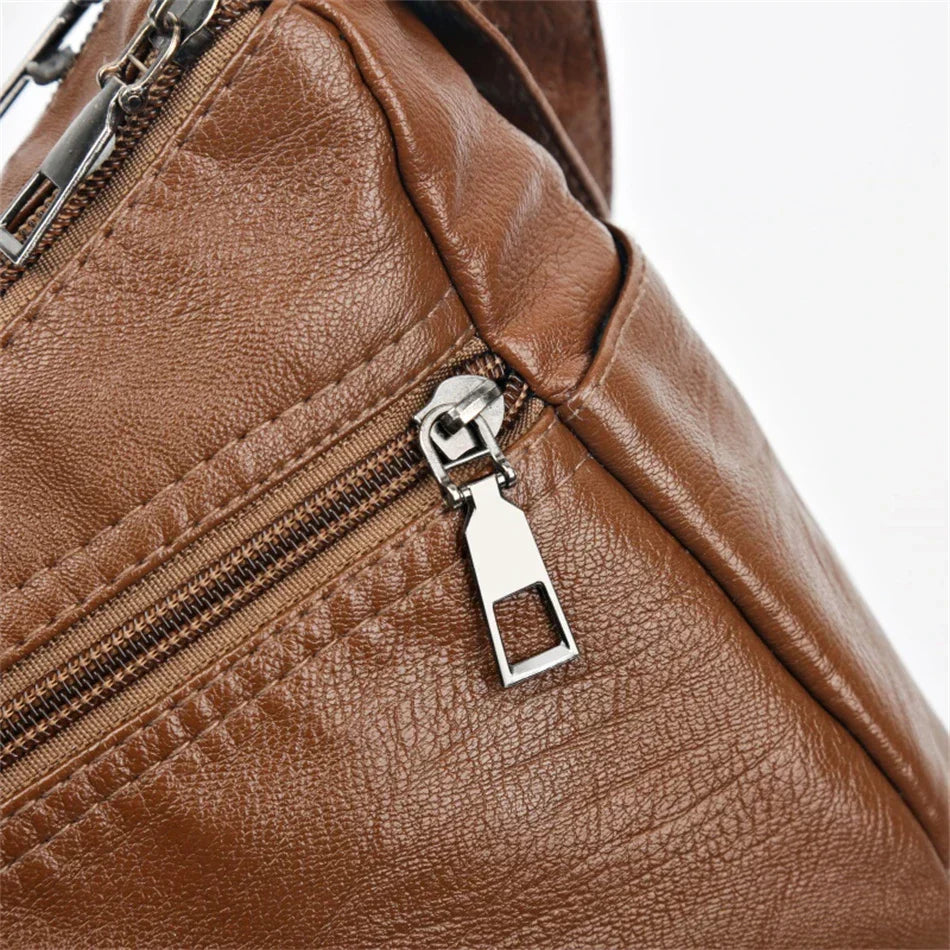 Brown leather crossbody bag close-up of zip pull and front metal lock detail