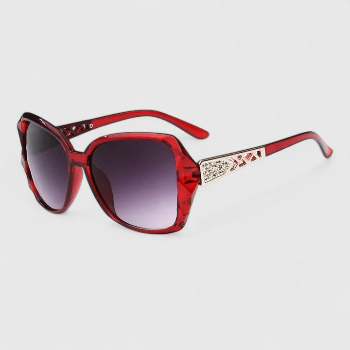 Red framed sunglasses with dark tinted lenses and rhinestone-accented temple bar