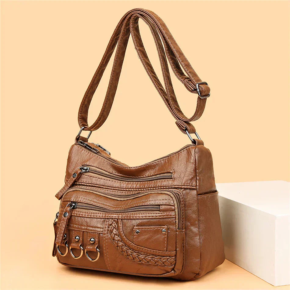 Brown multi-layer crossbody bag with zip pockets, braided front panel, and ring key straps
