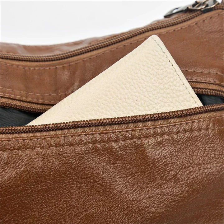 Brown leather crossbody bag close-up of top zipper and textured panel pocket insert