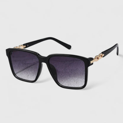 Square black sunglasses with purple gradient lenses and gold chain hinge detail