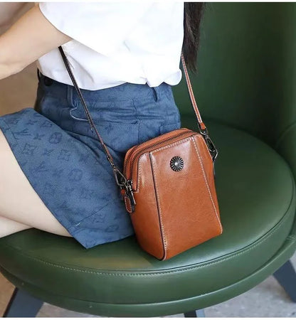 Orange-brown mini crossbody handbag with zipper and sunburst emblem