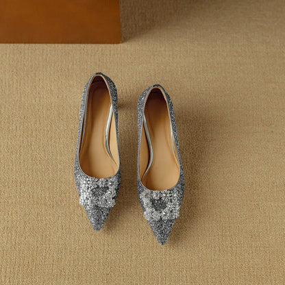 Silver glitter pointed-toe pumps with decorative bow at the toe, pair view