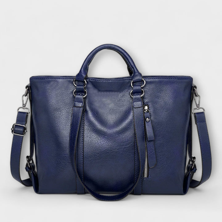 Large leather bag with top handles, side zippers, and crossbody straps in blue.