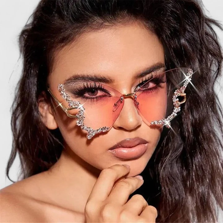 Rhinestone cat-eye sunglasses with reddish lenses and star-like gold accents