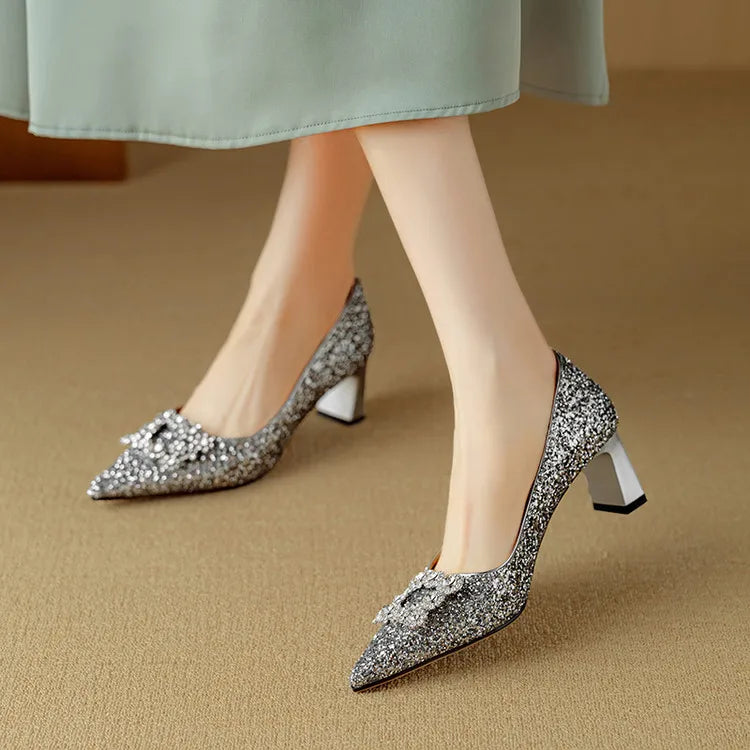 Silver-toned glitter pumps with pointed toe, jeweled bow, and low block heels