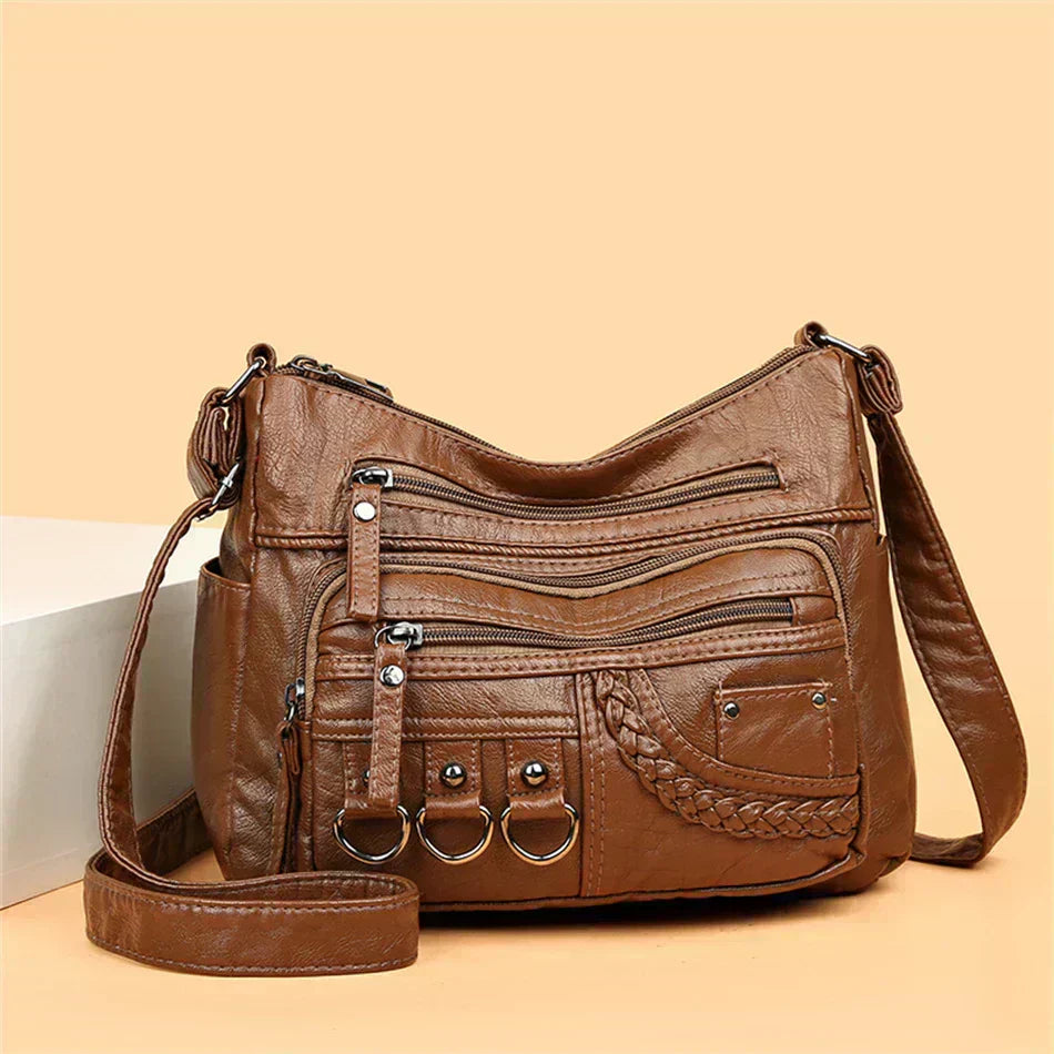 Brown multi-layer crossbody bag with long strap, multiple zippers, and braided front pocket