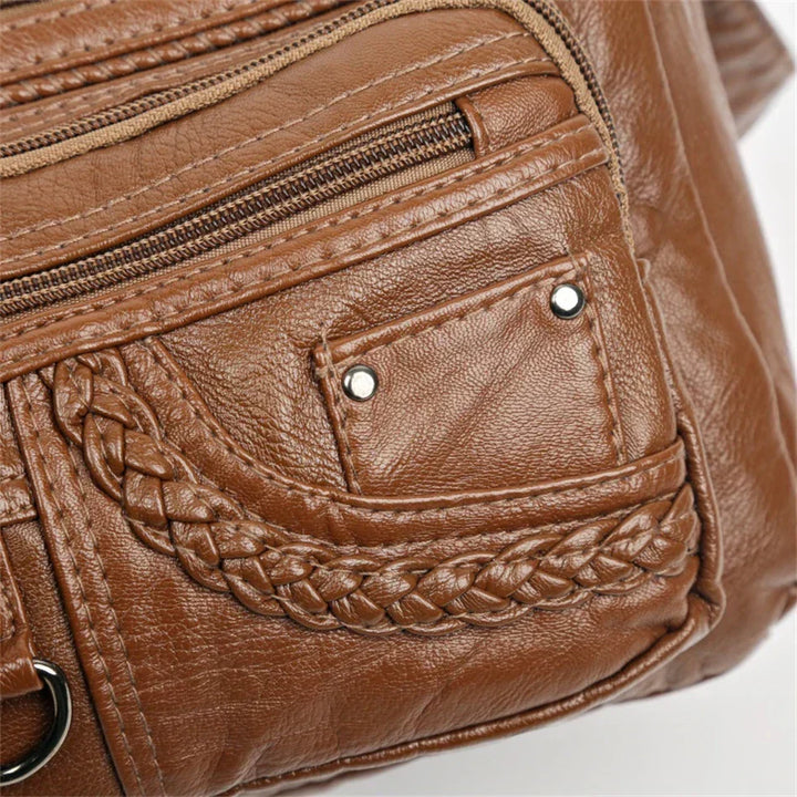 Brown leather multi-layer crossbody bag side pocket with snap hardware and braided detail