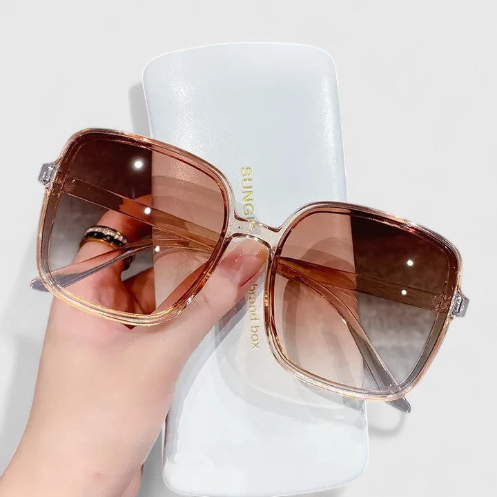 Elegant sunglasses with rose-gold frame and brown tinted lenses, wide square shape.