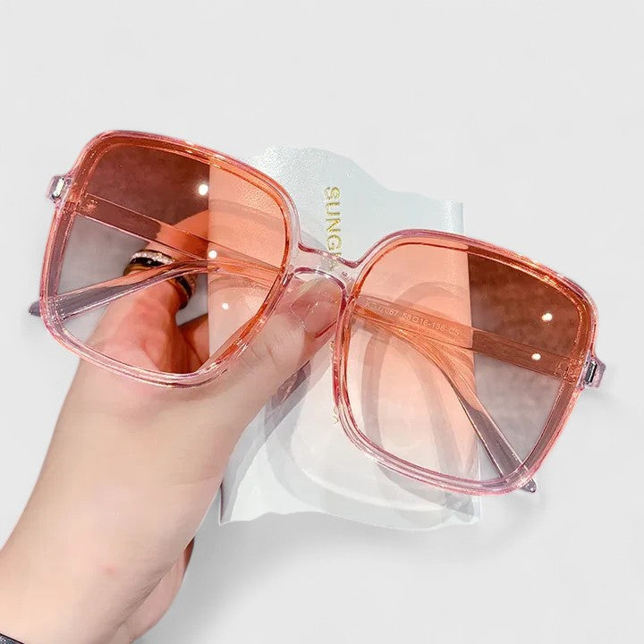 Elegant sunglasses with orange-red frame and amber tinted lenses, oversized square style.