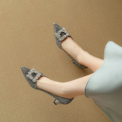 Silver glitter pointed-toe pumps with slim block heel and bow-like gem detail at top
