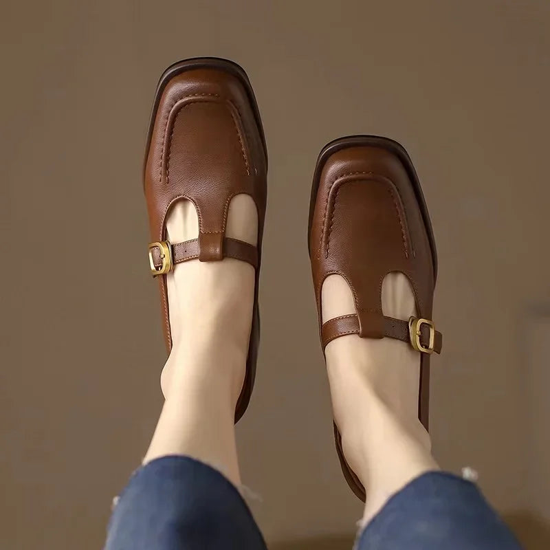 Brown T-strap loafers with buckle strap over a cutout front
