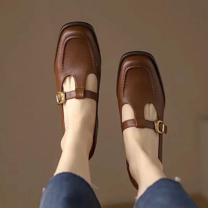 Brown T-strap loafers with buckle strap over a cutout front