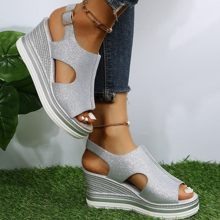 Silver glitter wedge sandals with ankle strap and peep-toe cutouts on textured sole