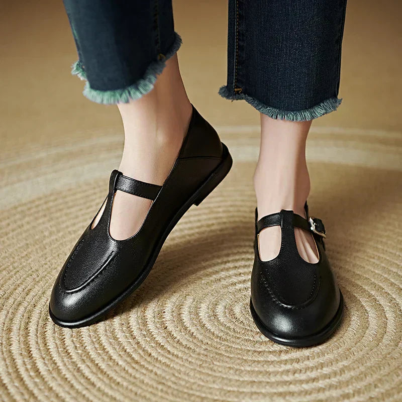 Black low-heeled Mary Jane pumps with T-strap and buckle, rounded toe.