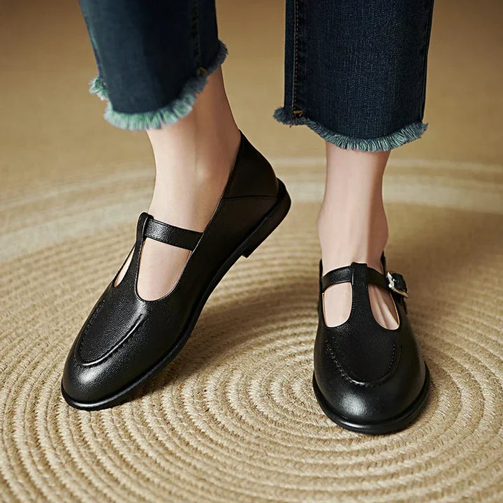 Black low-heeled Mary Jane pumps with T-strap and buckle, rounded toe.