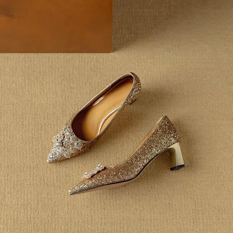 Pair of gold-toned glitter pumps with pointed toes and jeweled bow detail