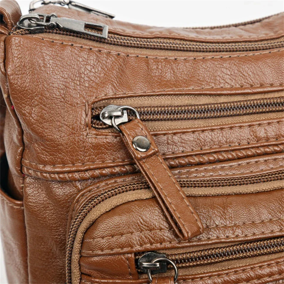 Brown leather multi-layer crossbody bag with braided trim and zippered front pocket
