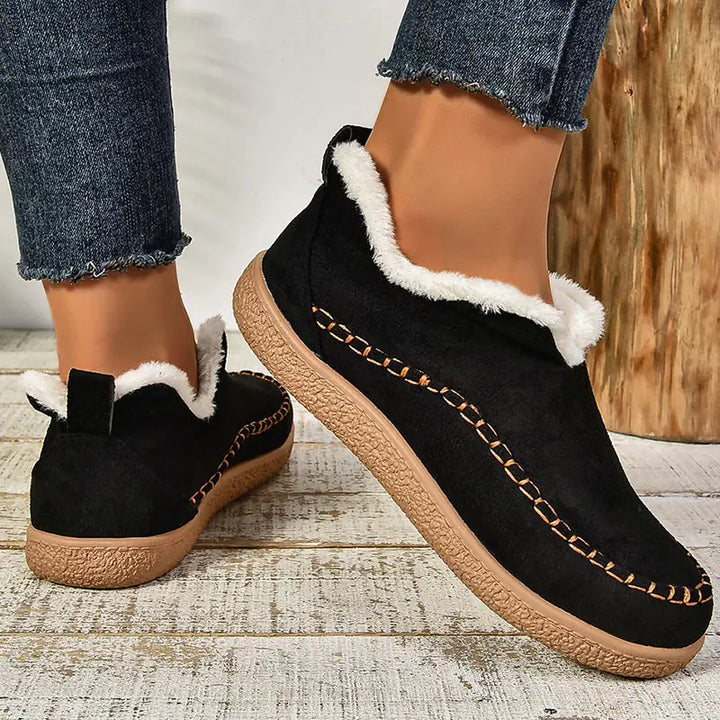 Black orthopedic slip-on slippers with fuzzy lining, stitched stripe, and tan sole