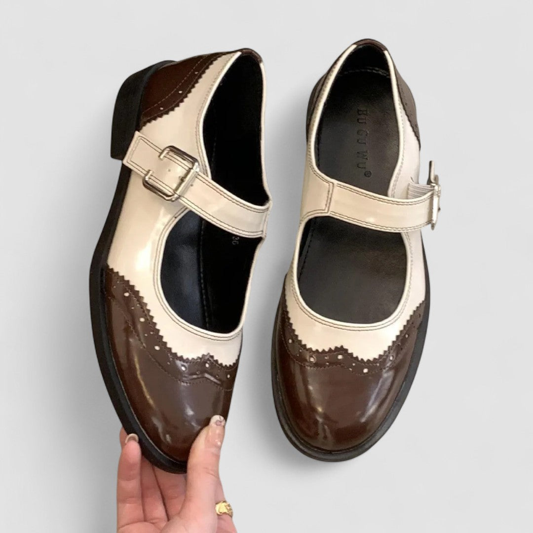 Brown Mary Jane shoes with cream strap, buckle, and brogue-style accents
