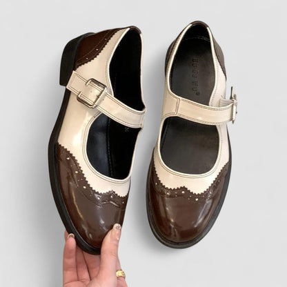 Brown Mary Jane shoes with cream strap, buckle, and brogue-style accents